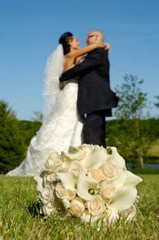 Wedding bouquet in grass in focus and couple in the background 