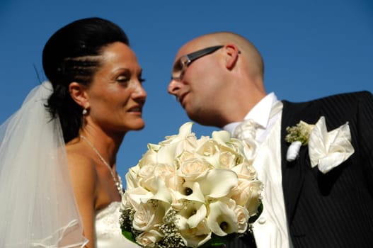 Bride and groom is showing their wedding bouquet while looking at each other.