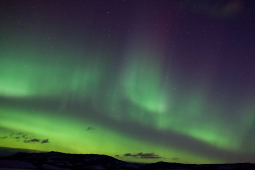 Colorful northern lights (aurora borealis) substorm on dark night sky with myriads of stars.