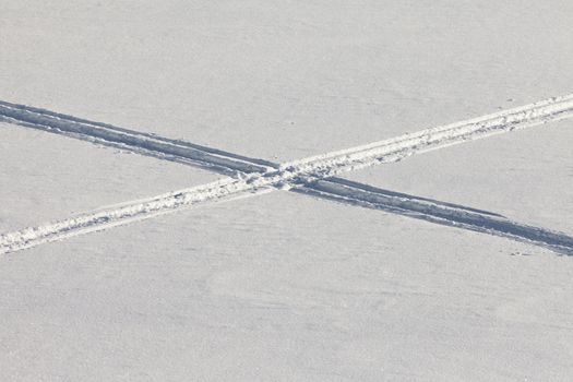 Crossing snowmobil tracks in otherwise untouched fresh powder snow surface.