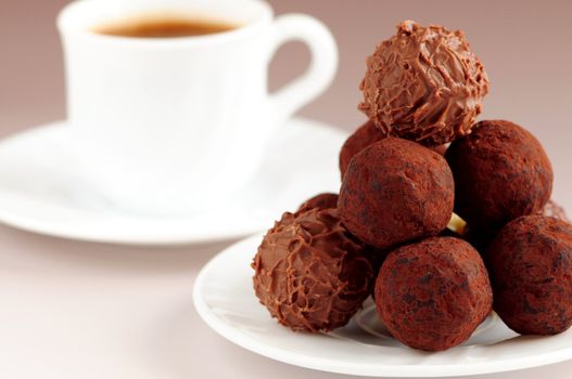 Gourmet chocolate truffles on a plate with a cup of coffee