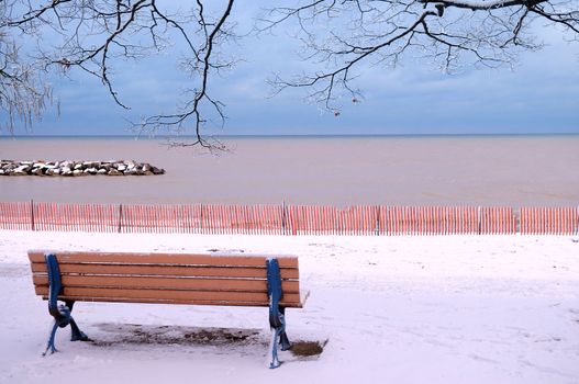 Winter park with a bench covered with snow. Beach area, Toronto, Canada.