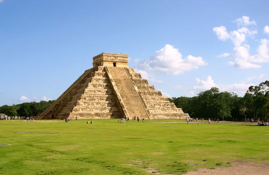 Antique mayan pyramid on green field over blue sky