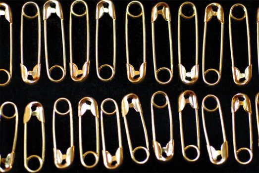 Golden safety pins in rows alternating upwards and downwards