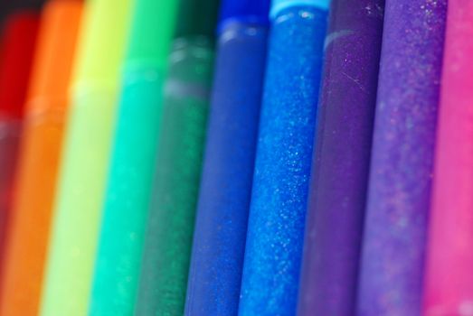 A row of bright glitter glue pens