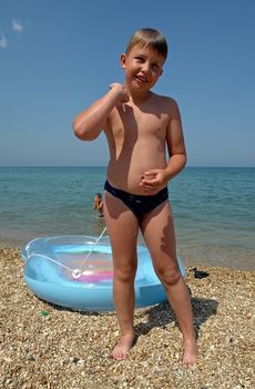 little boy pulls inflatable boat on the beach