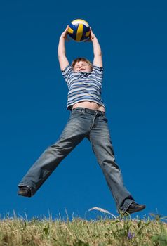 A little boy plays a ball with sky at background