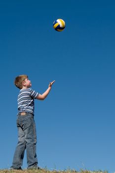 A little boy plays a ball with sky at background