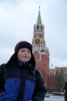 Winter. Little tourist in Moscow with Kremlin tower at background.