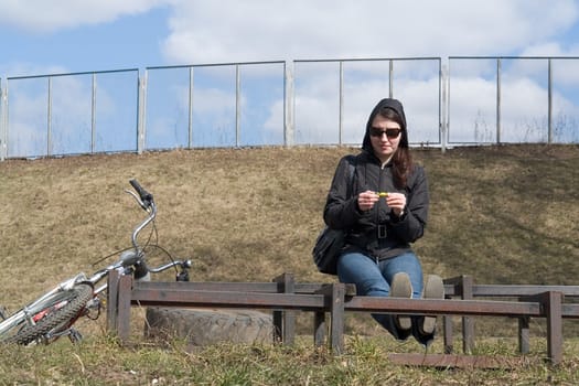 Spring. Woman rests on the bench after bicycle jaunt.
