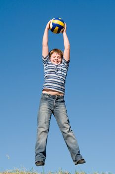 A little boy plays a ball with sky at background