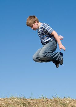 A little boy jumps with sky at background