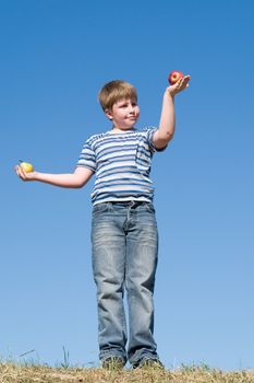 Difficult selection. Apple or pear? Boy with sky at background.