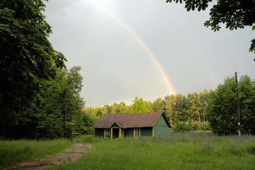 Rainbow after rain above the old house in a forest