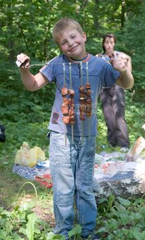 Boy shows freshly-fire shashlik on the spit