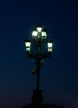Night. Ancient street lamp emits greenish light.