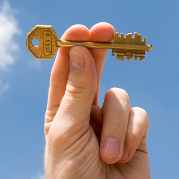 hand transfers the key with sky at background