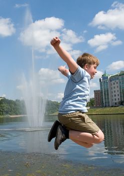 A little boy jumps with river at background 