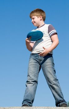 A little boy throws a flying disk with sky at background