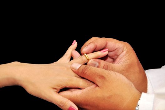 Wedding ceremony moment where the groom places the wedding ring on the brides finger.