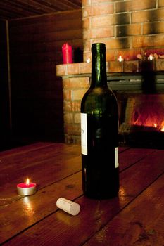 Wine bottle standing on table before burning fireplace