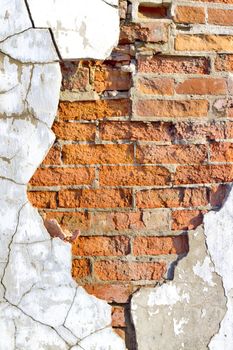 old brick wall with crumbling plaster cracked