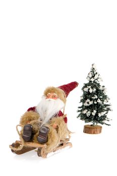 Miniature of Santa Claus on sleigh and a pine tree with snow, on white reflective background.