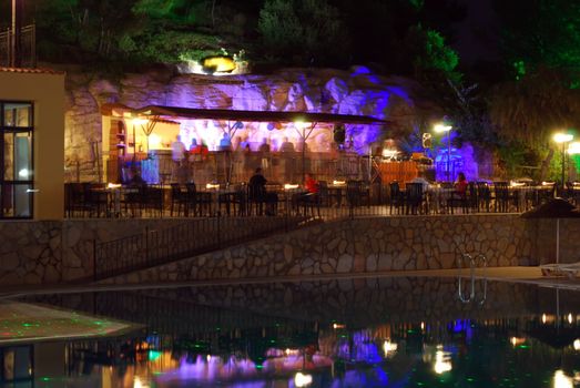 Night Bar with People Sitting and Talking at Tables and Bar, Having Rest at the Hotel