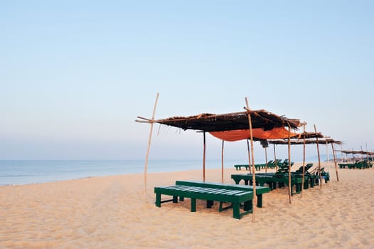 Exotic lean-tos of palm leaves and deck-chairs on the beach