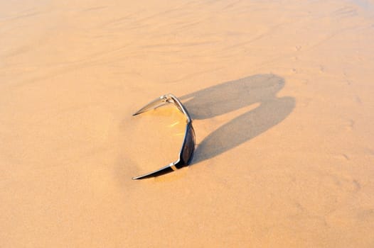 Sun glasses on the sandy beach at the sea