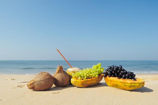 Papaya, coconut, nut and grapes on the sandy beach