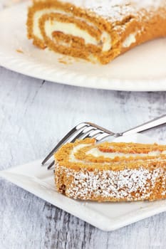 Slice of pumpkin roll with more in background.