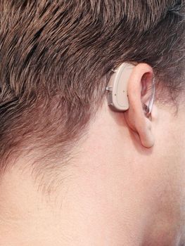 close-up of a man head with a behind-the-ear-hearing device.