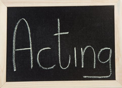 A black board with a wooden frame and the word 'ACTING' written in chalk.