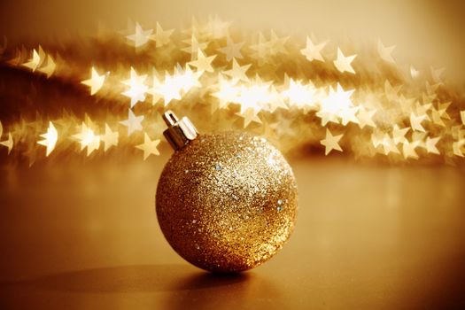 golden christmas ball on golden star bokeh background