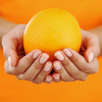 orange in woman hands close up