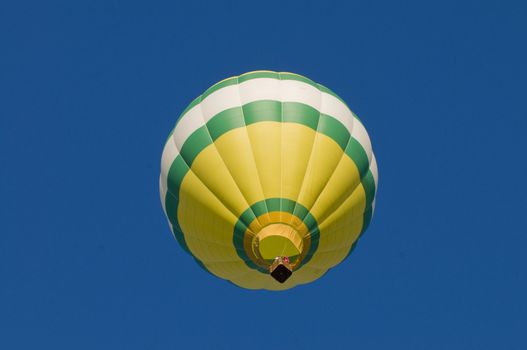 Green, white and yellow hot-air balloon airborne, shot from beneath