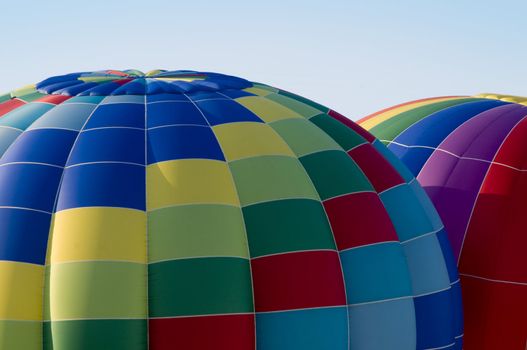 Top sections of colorful hot-air balloons inflating or ascending