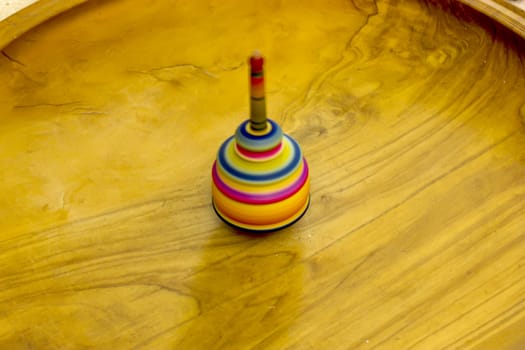 Colorful wooden spinning top on wood floor.