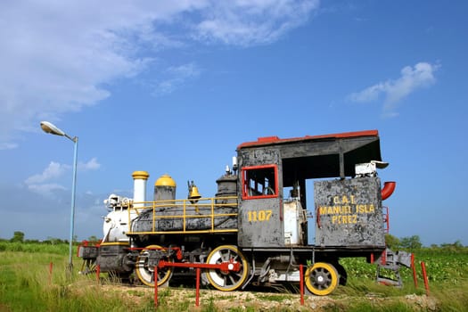 Old steam train rusting in tropical heat and humidity, Cuba under a blue sky