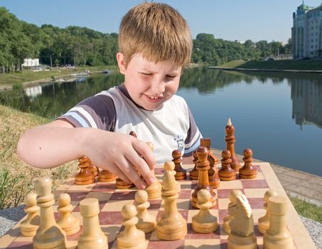 A little boy chess with river at background