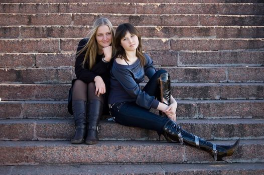 Two girls sit on steps in park