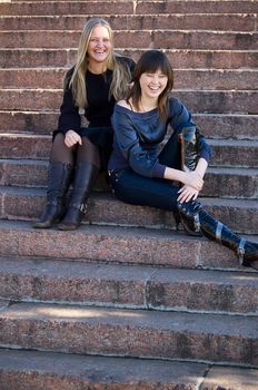 Two girls sit on steps in park