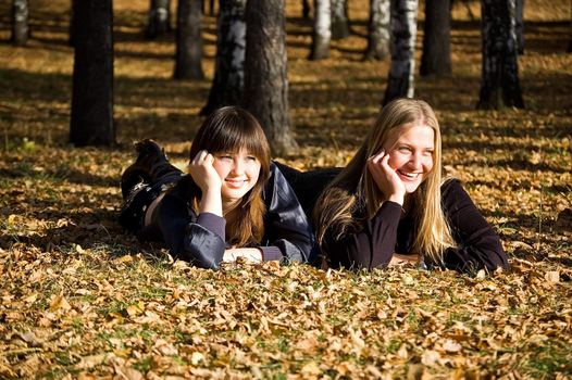 Two girlfriends on autumn leaves