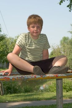 A little boy sits on gymnastic bars