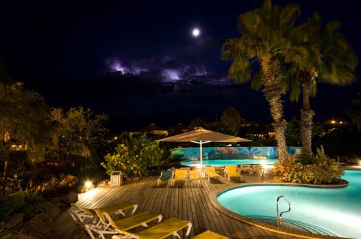 swimmingpool at night with thunder in the back