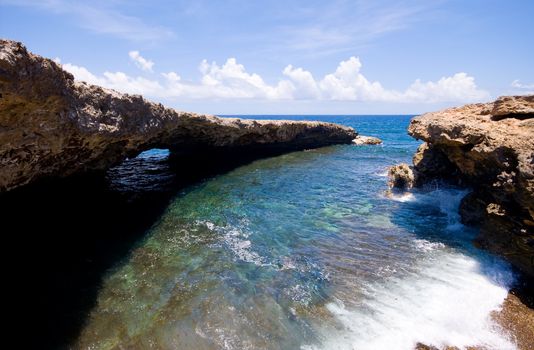rocky shore with ocean waves with natural bridge