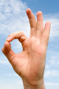 OK` hand gesture with blue sky at background