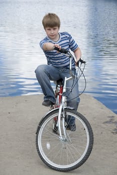 Boy on a bicycle with river at background
