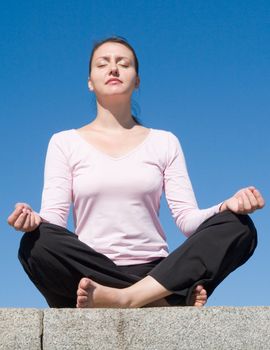 Meditation. The girl meditates with sky at background.